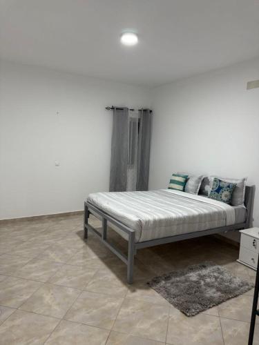 a bed in a room with a white wall at Casa Cucuia in Praia