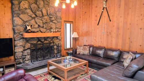 sala de estar con sofá de cuero y chimenea de piedra en Bear Cabin - 5min walk to village & 12 SHARC passes, en Sunriver