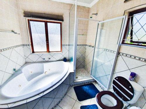 a bathroom with a tub and a shower and a toilet at Tranquil Coastal Home with Pool Family-Friendly Stay in Uvongo Beach