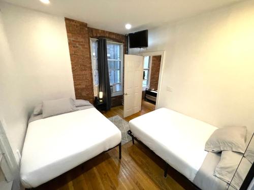 two beds in a small room with a window at Nestel Nest 1 bedroom apartment in New York