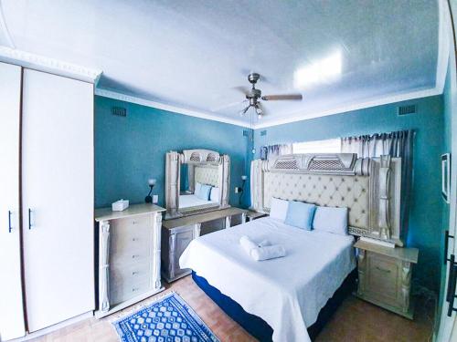 a blue bedroom with a bed and a mirror at Tranquil Coastal Home with Pool Family-Friendly Stay in Uvongo Beach