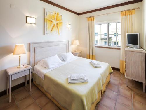 a hotel room with a bed and a television at Seasise apartment in Benagil in Benagil