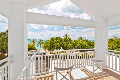 a balcony with two chairs and a view of the ocean at Airlie Beach Hotel in Airlie Beach