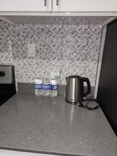 a tea kettle and bottles of water on a kitchen counter at Comfy and cozy in Kingston
