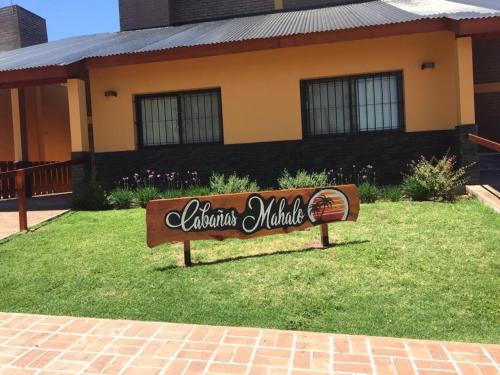 a sign in the grass in front of a house at Cabañas MAHALO in Villa Rumipal