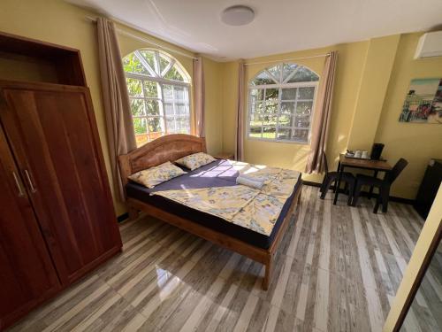 a bedroom with a bed and a table and two windows at Sondol Guesthouse in Loon