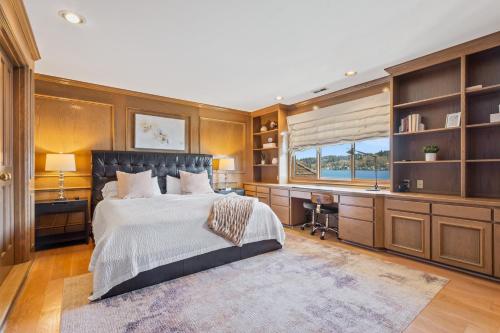 a bedroom with a bed and a desk and a window at Stunning Waterfront Mansion with Pool and Hottub in Mercer Island