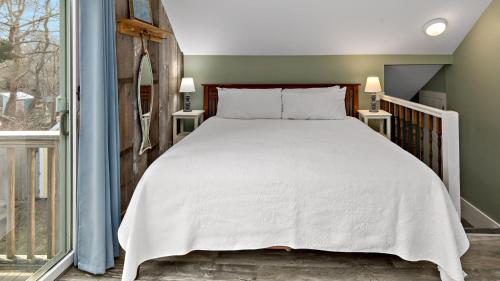 a bedroom with a bed and a large window at Inn at the Oaks in Eastham