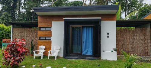 a small house with two white chairs in the yard at Villa Rios in Talamanca