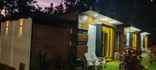 a house with yellow doors and white chairs in the yard at Villa Rios in Talamanca