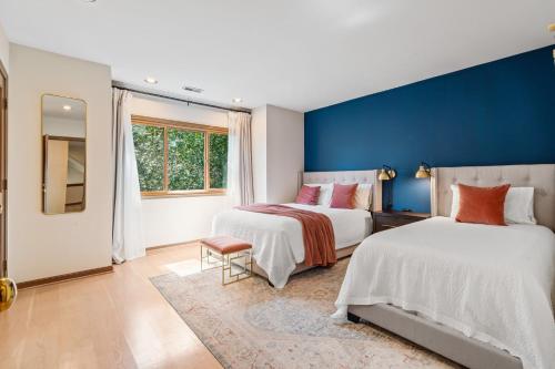 two beds in a room with a blue wall at Stunning Waterfront Mansion with Pool and Hottub in Mercer Island
