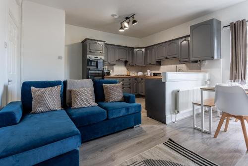 a living room with a blue couch and a kitchen at Gateshead 4 BR Home for Serenity Stay in Gateshead