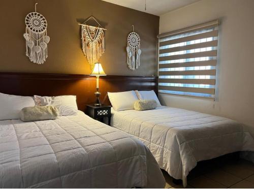 a bedroom with two beds and a lamp and a window at Departamento Residencial Campestre in Chihuahua