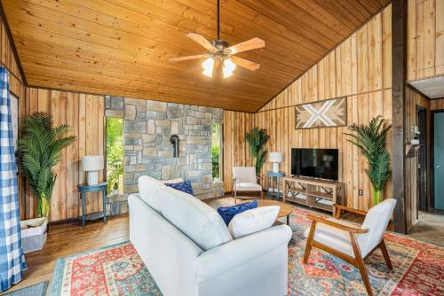 a living room with a ceiling fan and a stone wall at Modern Cabin w Mountain View Hot Tub & Fire Pit in Morton Grove