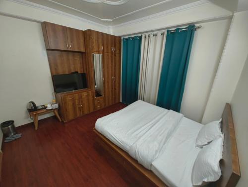a bedroom with a white bed and blue curtains at Fair lawns Home Stay in Shimla
