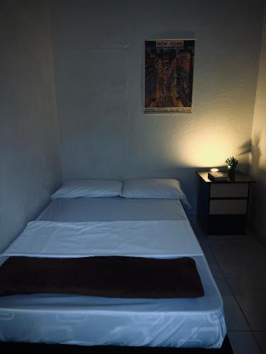 a bedroom with a white bed with a night stand at Hostal Mamaquilla in Pasto