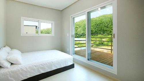 a bedroom with a bed and a large window at Hongcheon stone brown Pension in Hongcheon