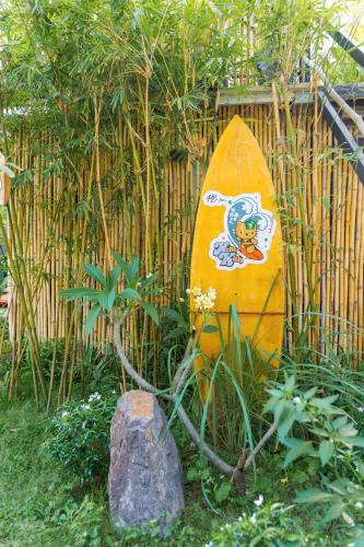 a yellow surfboard sitting in front of a fence at PBrooms in Mui Ne