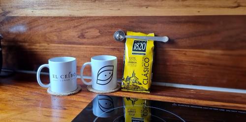 two coffee mugs sitting on a wooden shelf at Ceibo Lodge in Bijagual