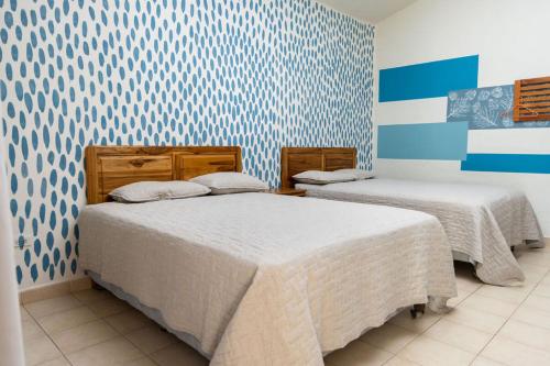 two beds in a room with blue and white wallpaper at Hotel Palmazul - Viña del Mar in Omoa
