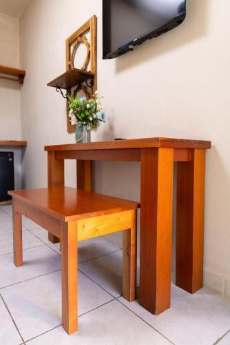 a wooden table with a bench and a tv on a wall at Hotel Palmazul - Viña del Mar in Omoa