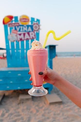 a person holding a milkshake on the beach at Hotel Palmazul - Viña del Mar in Omoa