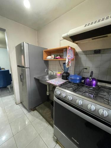 a kitchen with a stove and a stainless steel refrigerator at Amplia casa para huéspedes in Oaxaca City