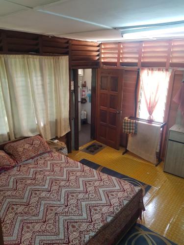 a bedroom with a bed and a window and a door at Roomstay "Ghumah Uwan" bilik kayu in Batu Kikir