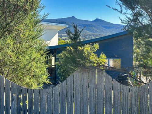 a fence in front of a house with mountains in the background at Boutara Holiday House in Falmouth