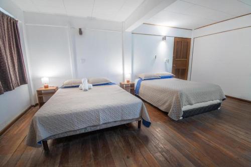 two beds in a room with wooden floors at Hotel el Tajalin in Montezuma