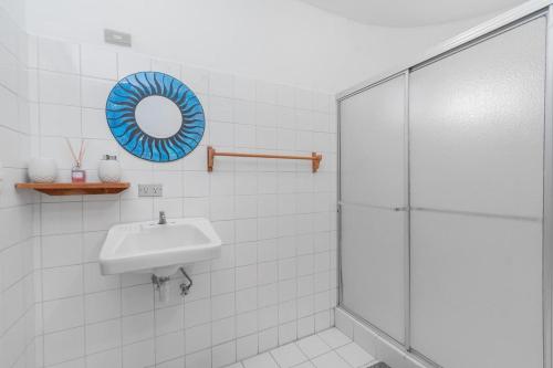 a white tiled bathroom with a sink and a shower at Hotel el Tajalin in Montezuma