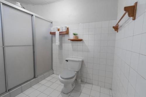 a white bathroom with a shower and a toilet at Hotel el Tajalin in Montezuma