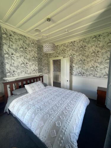 a bedroom with a large bed with floral wallpaper at Islay House - stylish villa in historic Lawrence in Lawrence