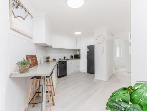 a kitchen with white walls and a black refrigerator at Cabarita Beachfront - Apartment 31 in Cabarita Beach