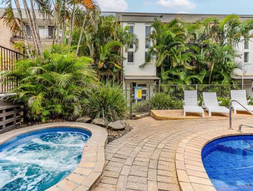 a swimming pool with two chairs and a building at Cabarita Beachfront - Apartment 31 in Cabarita Beach