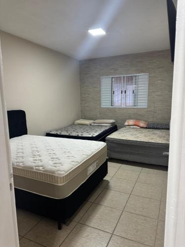 a room with three beds and a window at Casa Ramos in Itanhaém