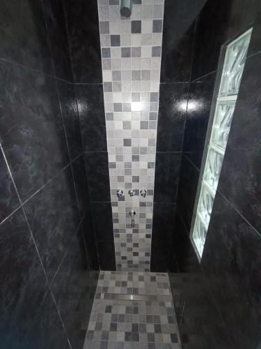 a shower with a tiled floor and two windows at The Herman House in Cerrillos