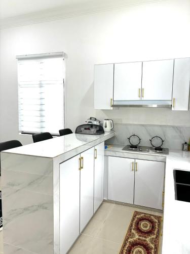 a white kitchen with white cabinets and a sink at Noafa Homestay Dungun in Kampong Nibong