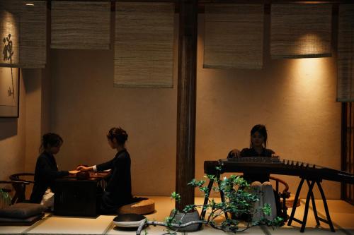duas mulheres sentadas em uma sala com um teclado em ChanYin Hotel em Chengdu
