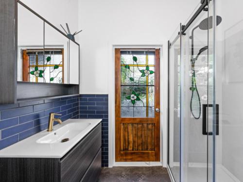 a bathroom with a sink and a glass door at Beautiful villa in Napier with spa in Napier