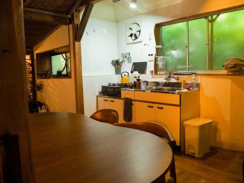 a kitchen with a table and a sink and a table and chairs at 海が目の前の秘境にある癒しの宿めぐりて in Setouchi