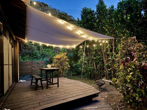 a wooden deck with a table and string lights at 海が目の前の秘境にある癒しの宿めぐりて in Setouchi