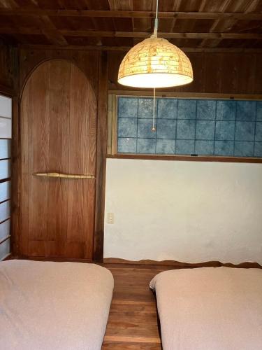 a room with two beds and a window and a lamp at 海が目の前の秘境にある癒しの宿めぐりて in Setouchi