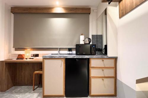 a kitchen with a microwave and a black refrigerator at Heritage Collection on Victoria - Mobile App Check-In in Singapore
