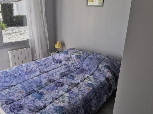 a bed with a blue comforter in a bedroom at Appartement cosy pour 2, centre-ville, proche plage, parking privé - FR-1-357-334 in La Tranche-sur-Mer