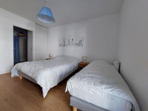 deux lits dans une chambre aux murs blancs dans l'établissement Appartement à 2 pas de la plage avec parking à Royan - FR-1-550-90, à Royan