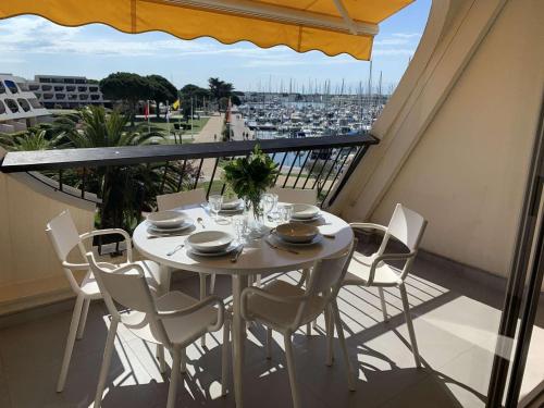 une table sur un balcon avec vue sur un port dans l'établissement Appartement 2 pièces avec piscine, 4 couchages à Port Camargue - FR-1-731-137, au Grau-du-Roi