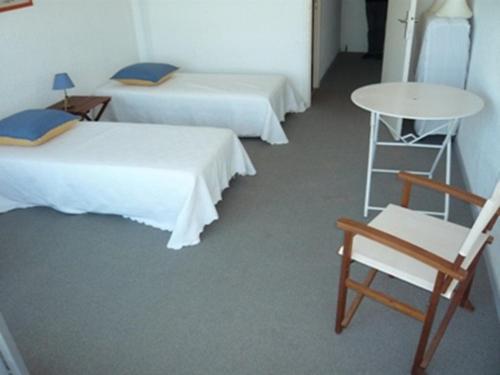 Cette chambre comprend deux lits, une chaise et une table. dans l'établissement Appartement 2 pièces avec piscine, 4 couchages à Port Camargue - FR-1-731-137, au Grau-du-Roi
