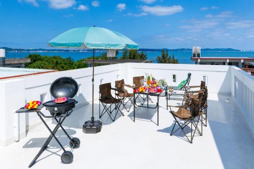 a patio with a grill and chairs and an umbrella at 海野Sea Terrace in Nanjo