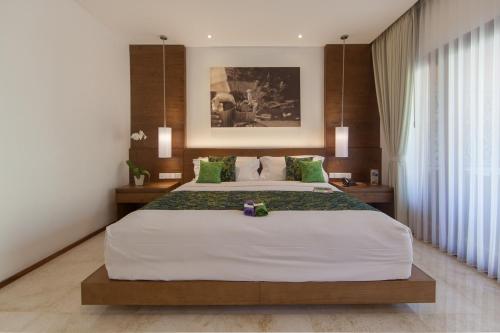 a bedroom with a large white bed with green pillows at Legian Beach Hotel in Legian